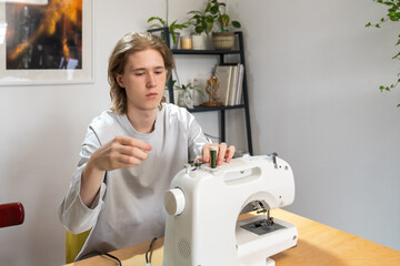 Boy threading sewing machine at home workspace