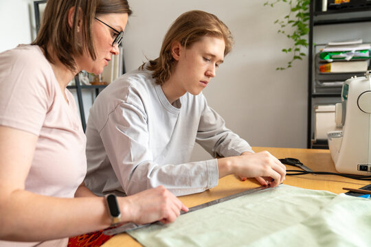 Mother and son sewing together at table