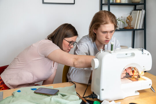 Mother Instructing Son on Sewing Machine Use