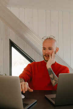 Focused individual working on multiple laptops in a bright workspace