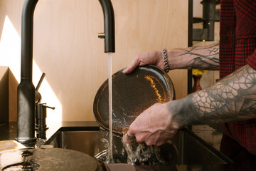Man washing dishes at home in modern kitchen setting