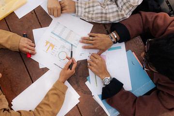 Group of unrecognizable people analyzing data and graphs.