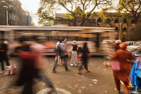 Busy street with people walking past a moving bus in Mumbai