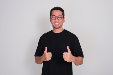 Adult Asian man smiling happy and give two thumbs up