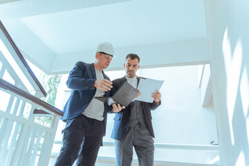 Architect and engineer reviewing blueprints at construction site