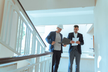 Architect and engineer reviewing blueprints at construction site