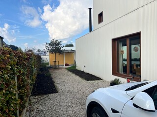 peaceful garden pathway leading to cozy home with electric car