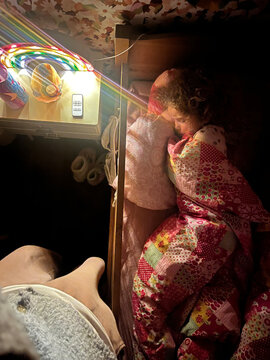 sleepy child tucked in colorful quilts brightened at night.