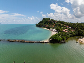 Expansive coastal view with lush greenery and calm turquoise waters under bright sunny skies. Koh Samui, Thailand.