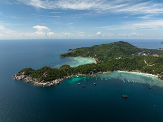 A tranquil bay with rocky shorelines surrounded by lush green hills and calm turquoise water. Thailand, Koh Tao.