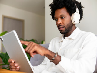 Focused Man Using Tablet While Listening to Music with Headphones