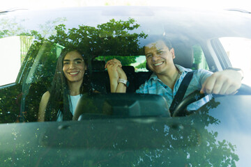 Happy couple holding hands while driving car