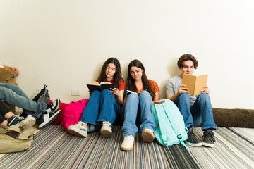 Teenage friends and high school students reading books at a book club at school