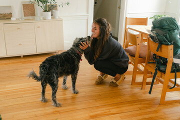 dog welcoming young woman with backpack coming home, 