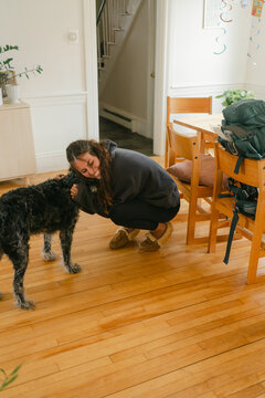 dog welcoming young woman with backpack coming home, 