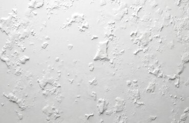 Fototapeta premium White wall rough texture background. Abstract plaster surface with uneven paint layer. Detailed view of construction design or interior renovation. Grunge background, architectural design element.
