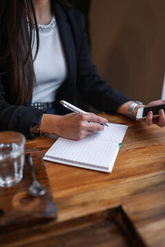 Young woman writing in diary at caf&eacute;