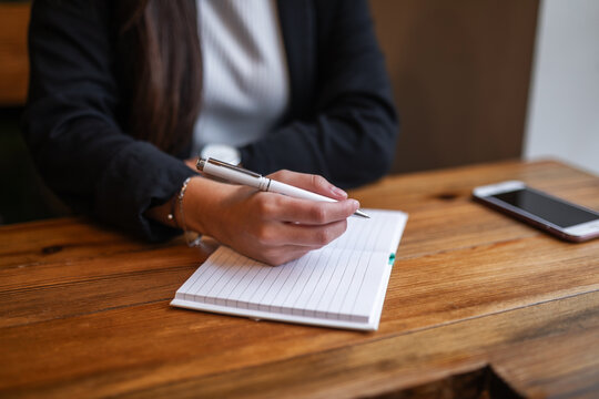 Young woman writing in diary at caf&eacute;
