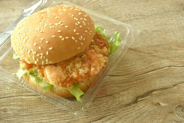 fried mashed shrimp hamburger and lettuce stuffed mayonnaise sauce with ketchup in plastic pakaging on table