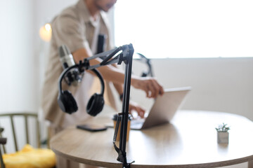 Man Arranging Podcast Studio Setup with Tech Equipment and Laptop for Content Creation.
