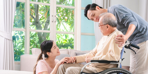 Fototapeta premium Asian family supporting their elderly loved one with care and compassion at home, symbolizing the importance of health insurance, life coverage, and family unity in aging with dignity and security