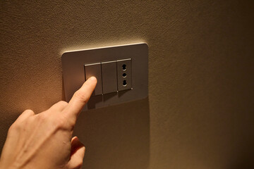 Hand pressing a light switch button 