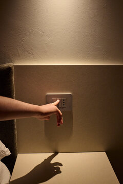 Hand pressing a light switch button 