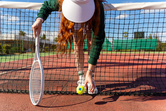 Tennis Player Picking Up Ball at Net

