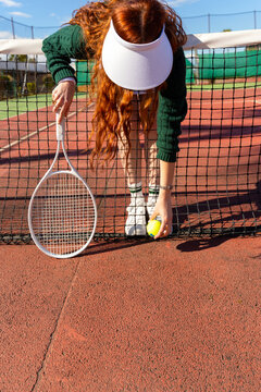 Tennis Player Picking Up Ball at Net

