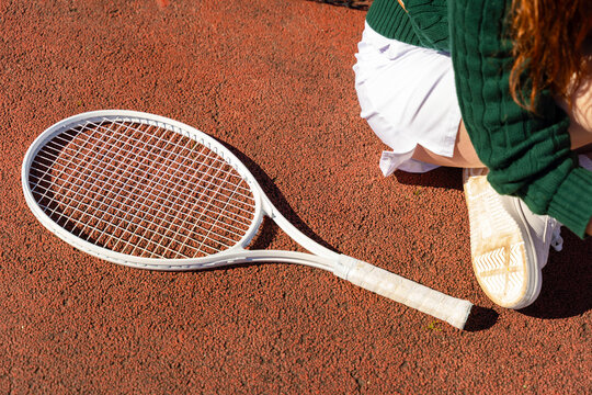 Tennis Racket on Clay Court Beside Player

