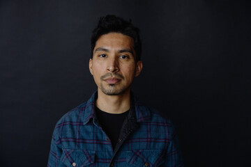 Man in Blue Plaid Shirt Against Dark Background