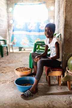 Young Senegalese Girl Shelling Peanuts in a Simple Room