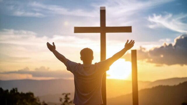 Silhouette of person with arms raised in praise and religious cross against vibrant sunset landscape sky background.