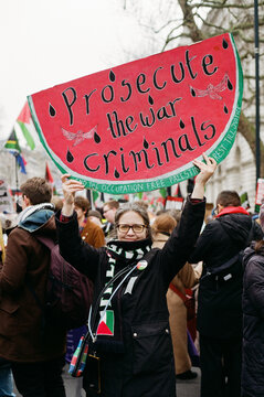 Woman holds placard in shape of watermelon at protest against genocide