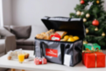 blur photo of christmas food delivery bag in new year interior, there is christmas tree in the corner of the room, blurry christmas wallpaper.