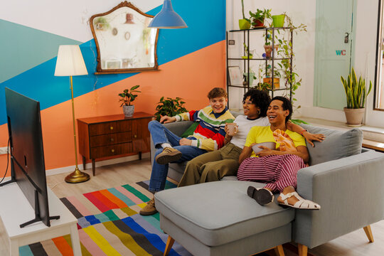 Happy friends watching tv relaxing on sofa