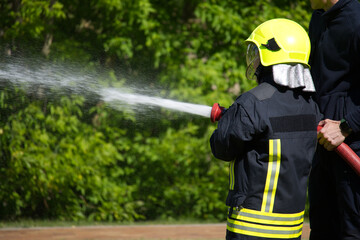 Fototapeta premium Child Learning Firefighting Techniques With Assistance in Outdoor Training Exercise