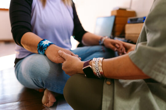 Women holding hands meditating together sitting on the floor
