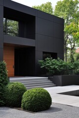 Obraz premium Modern black house design in a serene garden with neatly trimmed bushes and a water feature, showcasing contemporary architecture and landscaping