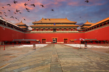 The Forbidden City sunset snow scene with flying pigeons.