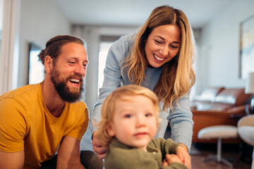 Happy parents playing with their toddler son at home