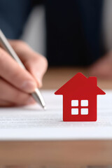 property loan mortgage qualification home concept. Signing documents with a house icon symbolizing real estate.