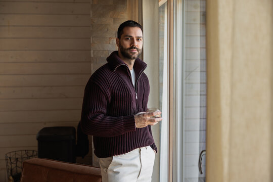 Portrait of a Man Relaxing Indoors by a Window Holding a Drink Glass
