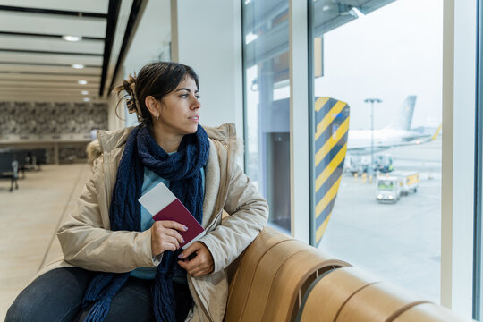 Woman holding passport and boarding pass waiting at airport