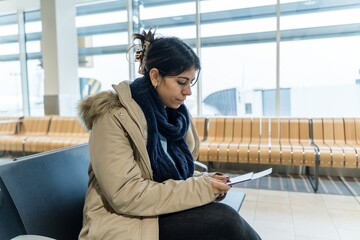 woman checking her passport and boarding pass while waiting 