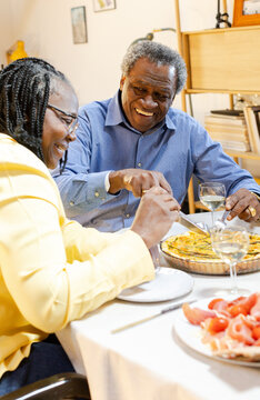 smiling senior couple sitting around dining table eating quiche