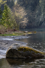 A large rock on the shore of a lake with a fishing rod in the background.