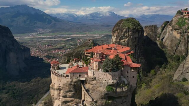 Wide drone of Meteora cliffs and Holy Trinity Monastery with scenic mountain establishing