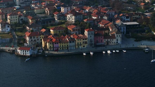 Charming lakeside town of Pella on Lake Orta, Italy, with colorful buildings, harbor, and moored boats. Aerial drone