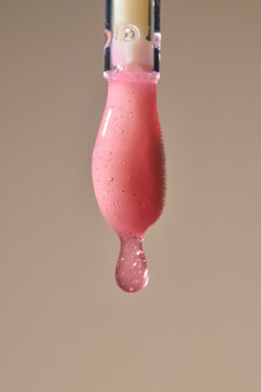 A drop of liquid lip gloss falls on the applicator. Closeup shot